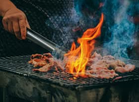 Close-up photo of man cooking meat on a BBQ