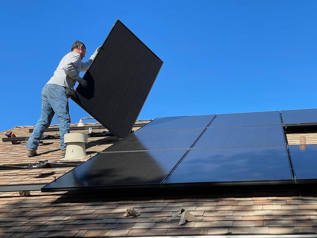 worker installing solar panels on a roof