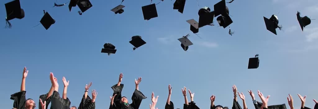 Newly Graduated People Wearing Black Academy Gowns Throwing Hats Up in the Air - cropped